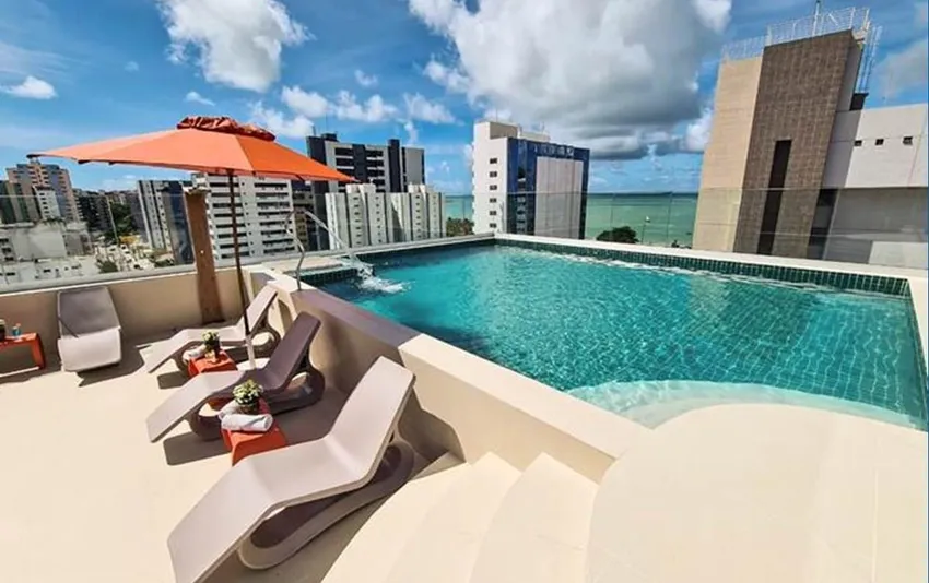 Foto de piscina com espreguiçadeiras, guarda-sol e vista para o mar.