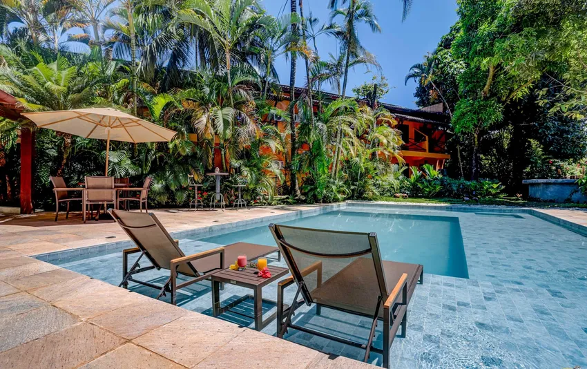 foto piscina com espreguiçadeiras e arvores