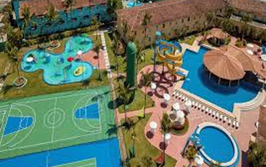 Foto aérea da área de lazer de um resort com piscinas, toboágua e quadra esportiva