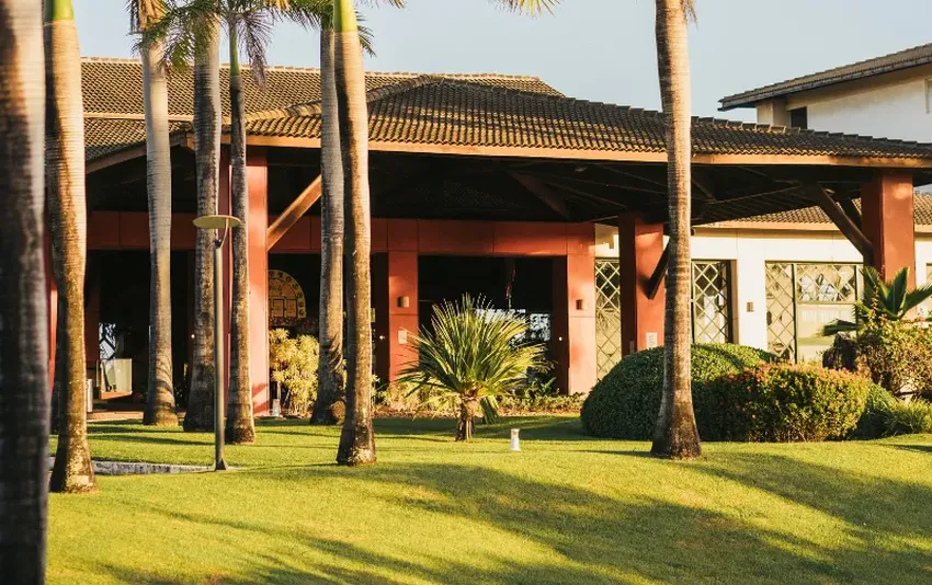 Foto do hotel e gramado com arvores