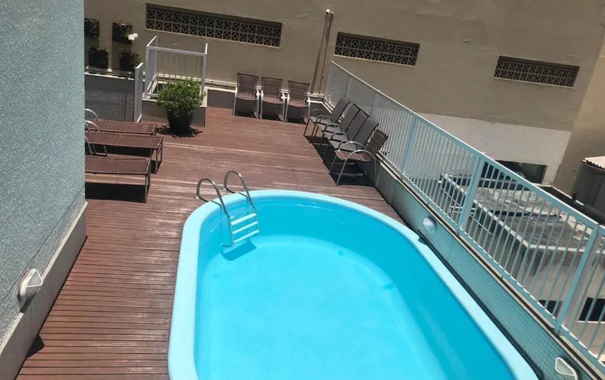 Foto de uma piscina azul em um deck de madeira com cadeiras ao redor