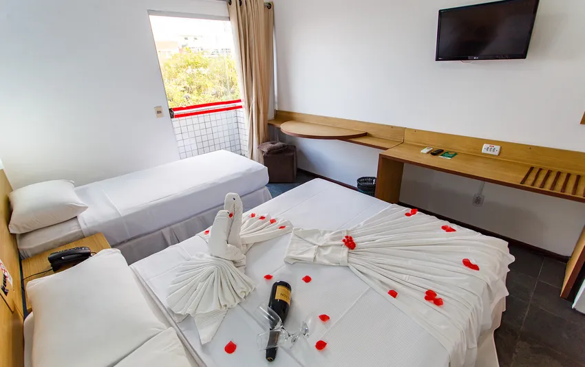 Foto de uma cama de casal decorada com pétalas e detalhes românticos