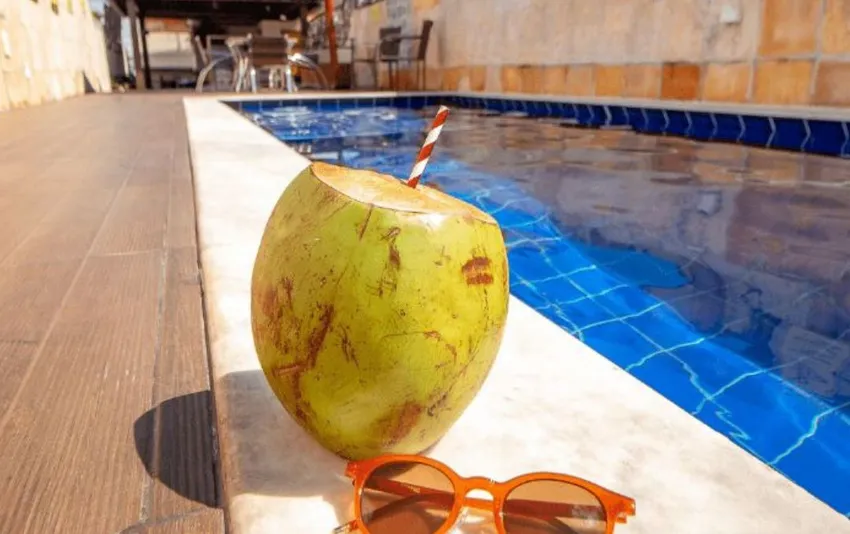 Foto de um coco com canudo ao lado da piscina, em área de lazer do hotel