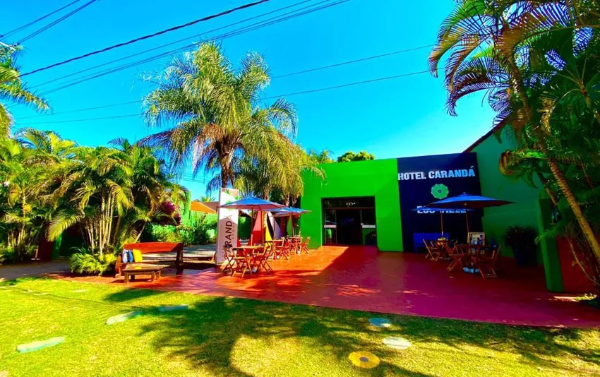Foto da entrada do hotel em estilo tropical, com jardins e palmeiras