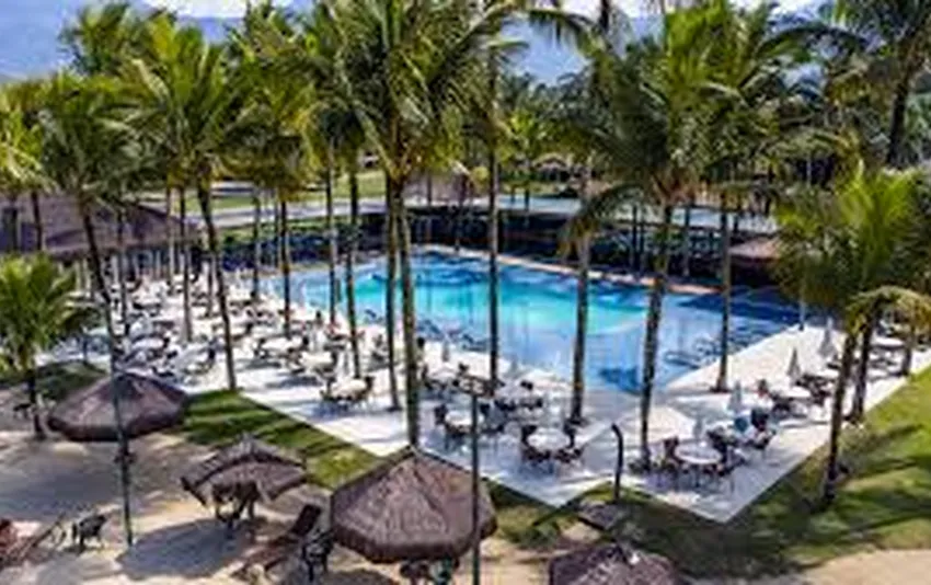 Foto piscina com coqueiros e quiosques em volta