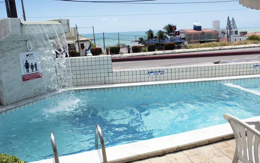 Foto da piscina do hotel vista por outro ângulo, com a praia ao fundo