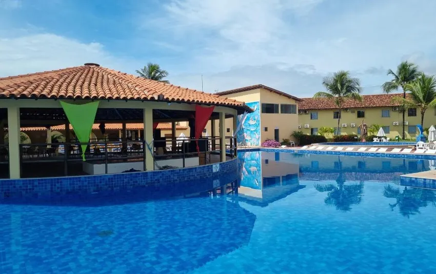 Foto de uma grande piscina de resort refletindo o céu com um quiosque