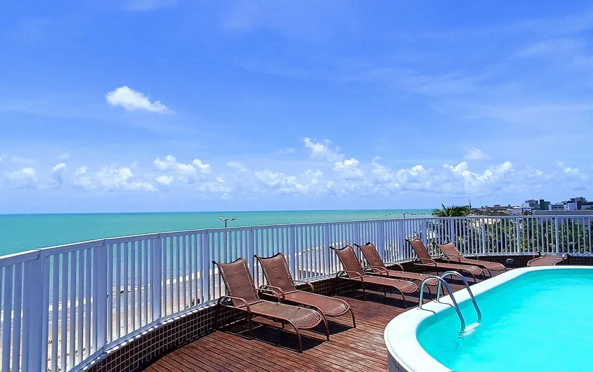 Foto de uma piscina em um terraço com espreguiçadeiras e vista para o mar