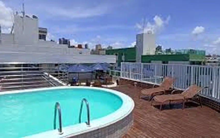 Foto de uma piscina no terraço com espreguiçadeiras e prédios ao fundo
