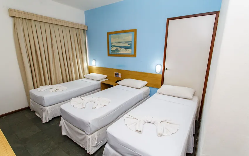Foto de um quarto com três camas de solteiro, preparado para acomodar até três hóspedes