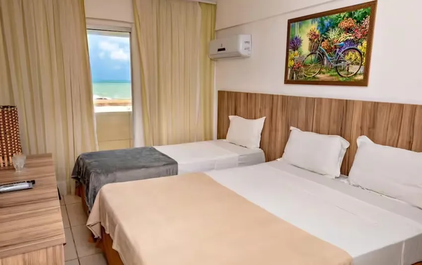 Foto de quarto com uma cama de casal, uma cama de solteiro e vista para a praia