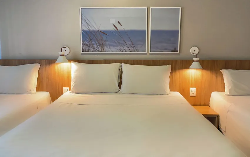 Foto de um quarto com uma cama de casal centralizada e duas camas de solteiro nas laterais