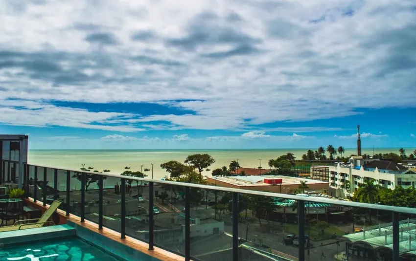Foto da vista de um terraço com piscina, mostrando a cidade e o mar ao fundo